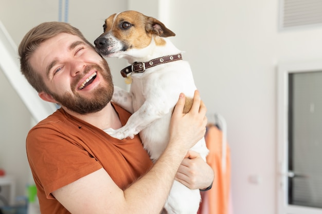 Concepto de animales, mascotas y personas - hombre sonriente en camiseta casual mostaza con su jack russell terrier.
