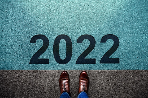 Concepto del año 2022. Vista superior del empresario de pie en la línea de salida. Prepárese para dar un paso adelante hacia el desafío de Año Nuevo. Foto de metáfora