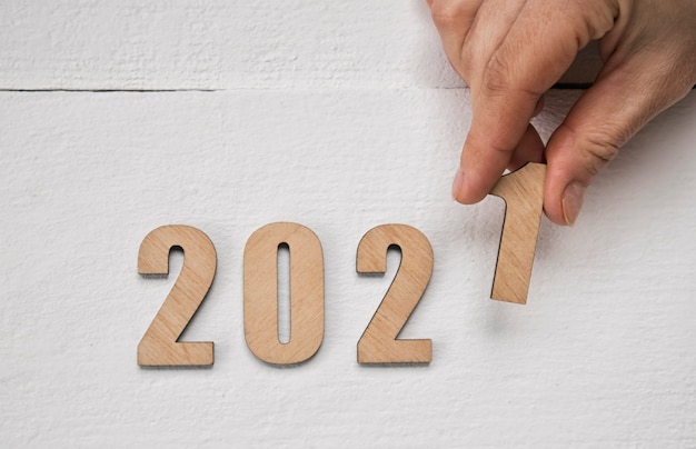 Concepto de año nuevo 2021. Mano femenina poniendo números de madera 2021 en la mesa de madera