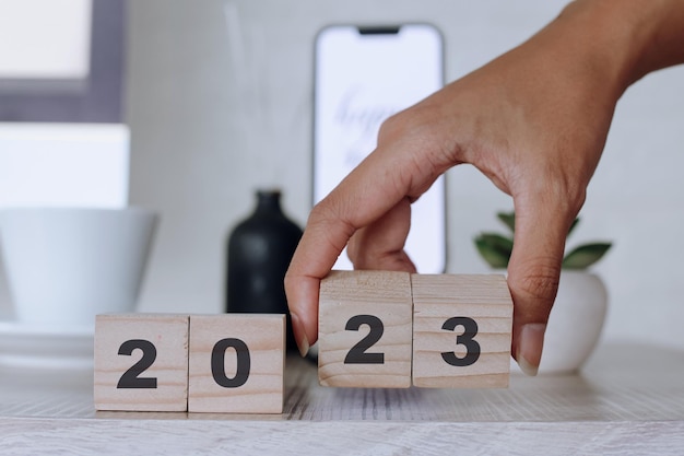 Concepto de año nuevo 2023, mano sosteniendo cubos de madera