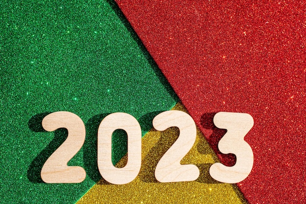 Concepto de año nuevo Números de madera 2023 en fondo estrellado brillante de oro verde rojo de tendencia multicolor Tarjeta de año nuevo
