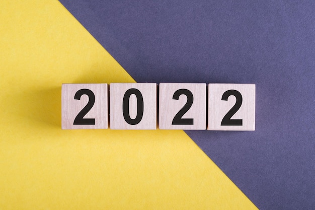 Concepto de año nuevo con texto 2022 en cubos de madera en escritorio gris-amarillo, nuevo comienzo. copia espacio