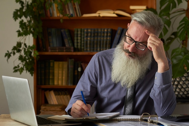 Concepto de aprendizaje a distancia. Profesor tutor mirando portátil y toma notas en un cuaderno