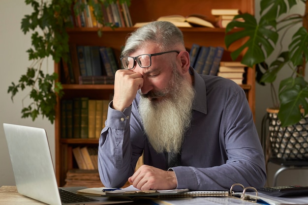 Concepto de aprendizaje a distancia. Profesor tutor molesto cansado mirando portátil y agarrando la cabeza