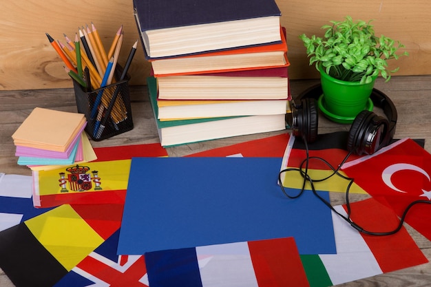 Foto concepto de aprendizaje de idiomas banderas de papel en blanco libros auriculares lápices sobre fondo de madera