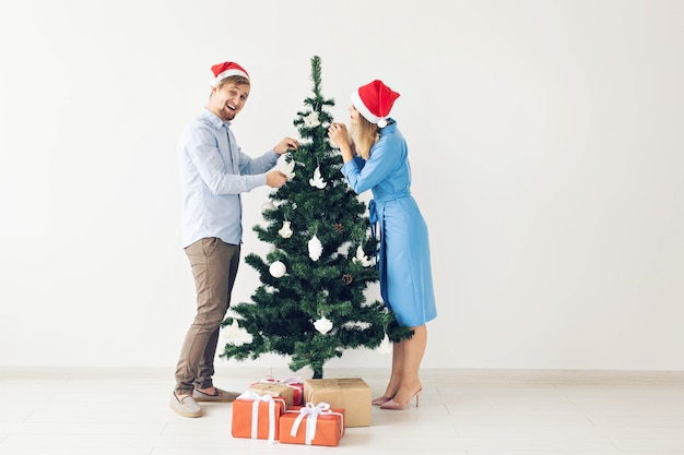 Concepto de árbol de Navidad y vacaciones - familia sonriente feliz con gorro de Papá Noel celebrando en casa.