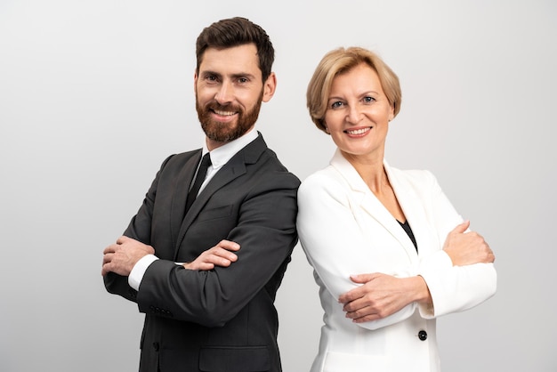 Concepto de asociación empresarial. Hombre joven y mujer mayor de pie espalda con espalda con las manos cruzadas contra el fondo blanco.