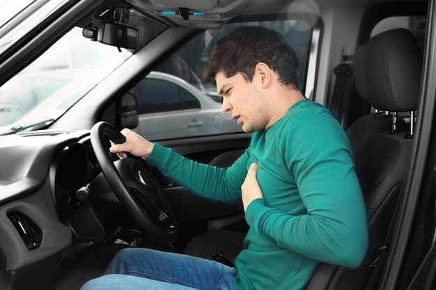 Foto concepto de ataque al corazón joven que sufre de dolor en el pecho sentado en el coche