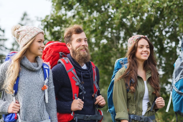 concepto de aventura, viajes, turismo, caminatas y personas - grupo de amigos sonrientes caminando con mochilas