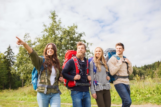 concepto de aventura, viajes, turismo, caminatas y personas - grupo de amigos sonrientes caminando con mochilas