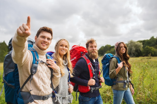 concepto de aventura, viajes, turismo, caminatas y personas - grupo de amigos sonrientes caminando con mochilas