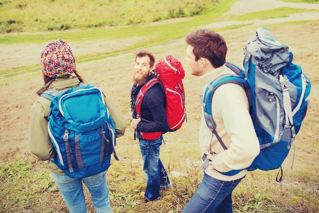 concepto de aventura, viajes, turismo, caminatas y personas - grupo de amigos sonrientes con mochilas al aire libre