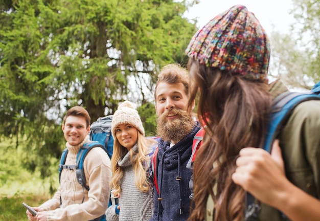 concepto de aventura, viajes, turismo, caminatas y personas - grupo de amigos sonrientes con mochilas y computadora de tablet pc caminando al aire libre