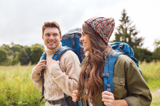 concepto de aventura, viajes, turismo, caminatas y personas - pareja sonriente caminando con mochilas al aire libre