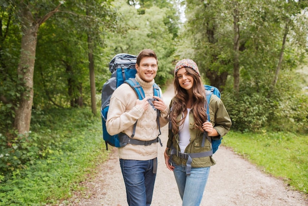 concepto de aventura, viajes, turismo, caminatas y personas - pareja sonriente con mochilas al aire libre