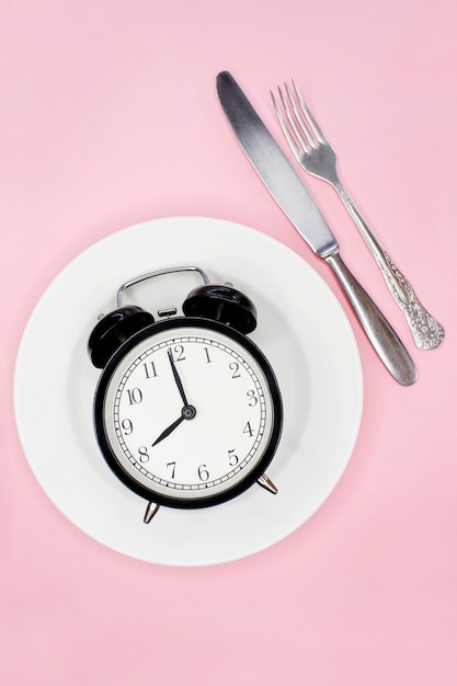 Foto concepto de ayuno intermitente dieta cetogénica pérdida de peso tenedor y cuchillo despertador en placa