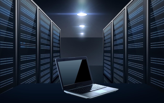 concepto de base de datos, computación y tecnología futura - computadora portátil con pantalla negra en blanco sobre el fondo de la sala de servidores