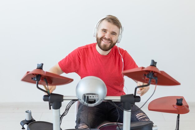 Concepto de baterista, tambor, música y personas - baterista joven tocando en la sala blanca