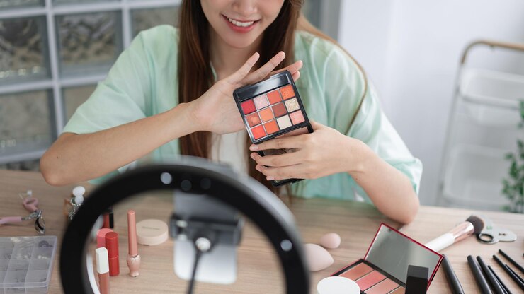 Foto concepto de beauty vlogger mujer joven muestra sombra de ojos para presentar el producto y grabar video para vlog