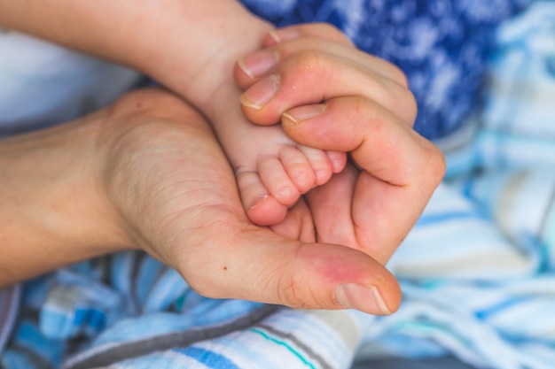 Foto concepto de bebé y recién nacido manos de la madre sosteniendo los pies del bebé recién nacido