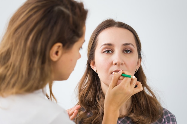 Concepto de belleza y cosmética - Artista de maquillaje haciendo maquillaje profesional de mujer joven.