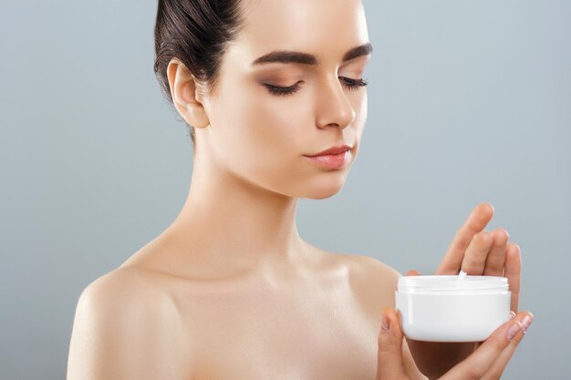 Concepto de belleza para el cuidado de la piel Mujer bonita joven con crema cosmética