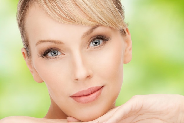 concepto de belleza, gente y cambio de imagen - hermosa cara de mujer joven sobre fondo natural verde