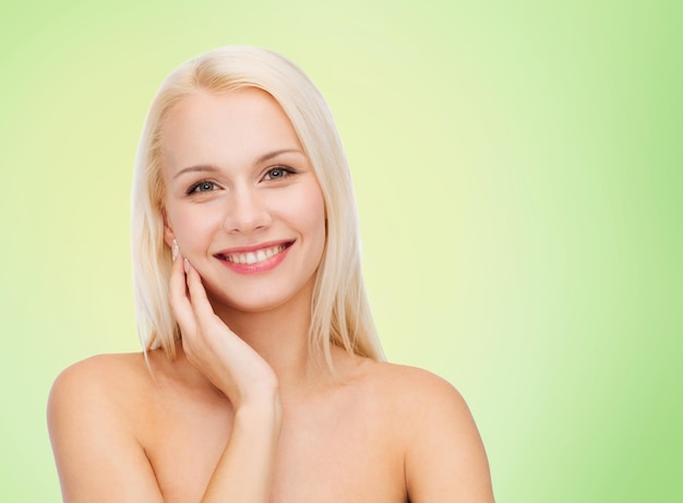 concepto de belleza, gente y salud - bella joven tocándose la cara sobre fondo verde