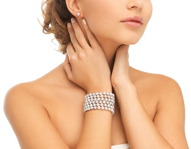 Concepto de belleza y joyería - hermosa mujer con aretes de perlas y pulsera