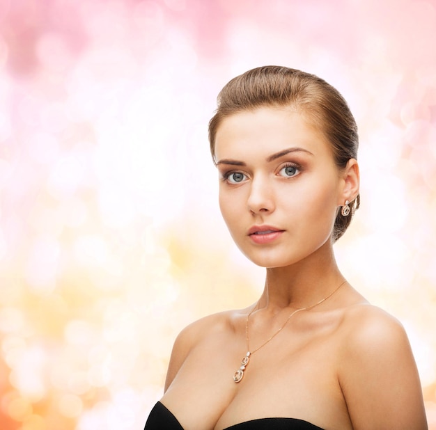 concepto de belleza y joyería - mujer con aretes de diamantes brillantes y colgante