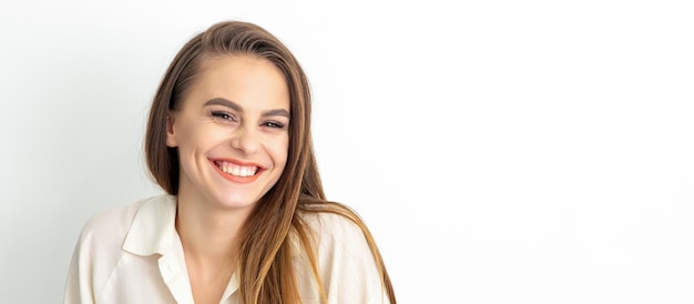 Concepto de belleza de mujer. Retrato de una mujer caucásica joven sonriente tímida encantadora feliz con el pelo largo castaño posando y mirando a la cámara sobre fondo blanco.