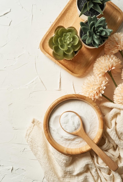 concepto de belleza de polvo de colágeno en un cuenco de madera y una cuchara sobre fondo de mesa blanco.