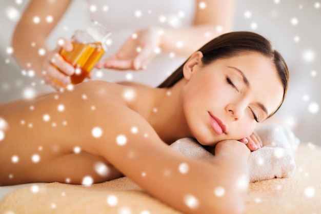 concepto de belleza, salud, vacaciones, gente y spa - hermosa mujer joven en el salón de spa recibiendo masaje con aceite