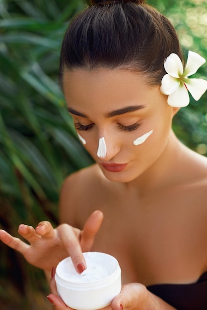 Concepto de belleza y spa para el cuidado de la piel facial Retrato de mujer con crema hidratante en la mano