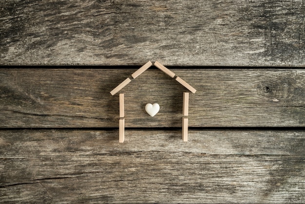 Foto concepto de bienes raíces con un corazón dentro del marco de una casa en una mesa en vista de ángulo alto.