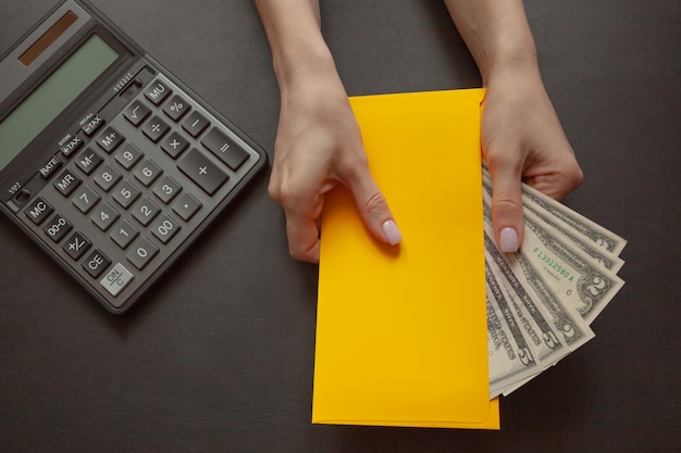 El concepto de bienestar financiero, la niña en su mano sostiene un sobre amarillo con dinero.