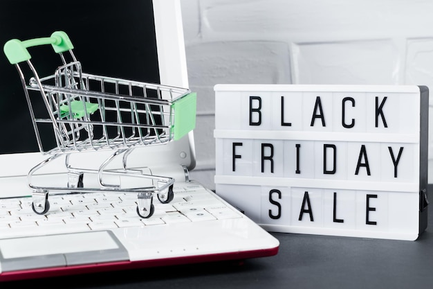 Concepto de Black Friday Mini carro de compras y laptop Venta y descuento en línea