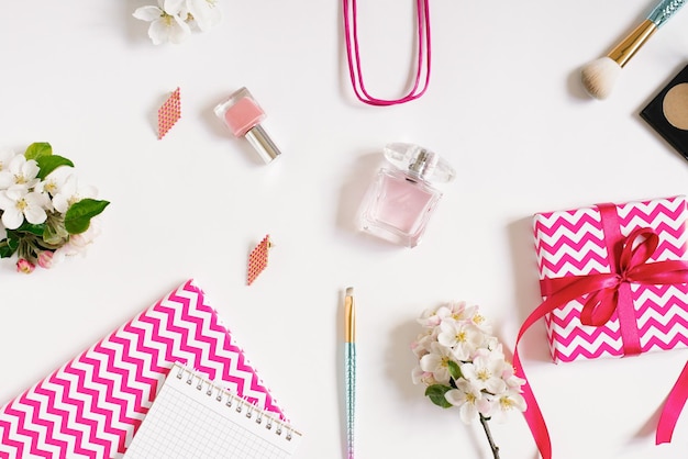 Concepto de un blog de belleza Accesorios para el maquillaje de las mujeres y delicadas flores de manzana sobre un fondo blanco Apartamento plano vista superior escritorio de mujeres con cuadernos en rosa