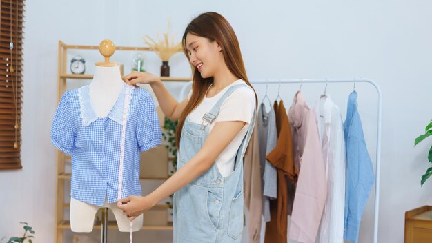 Concepto de blogger de moda Las mujeres asiáticas miden la longitud de la camisa para presentar y vender en transmisión de video