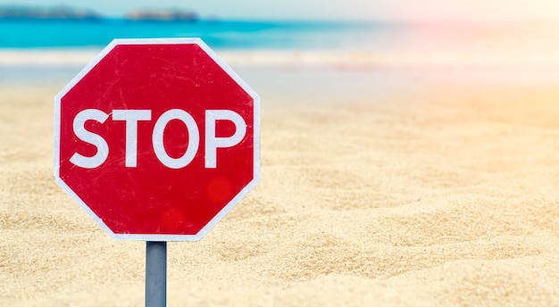 Concepto de bloqueo. Señal de pare en la playa junto al mar.