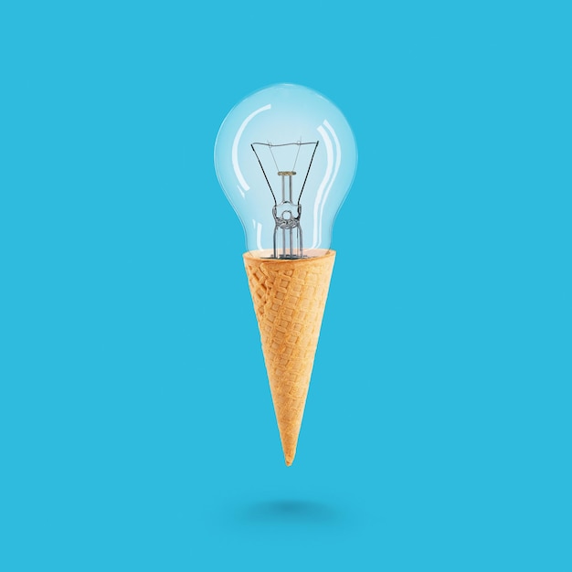Concepto de bombilla con cono de galleta de helado sobre fondo azul Idea creativa