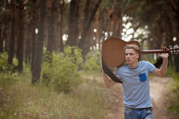 Concepto de bosque de paseo de hombre guitarrista cansado.