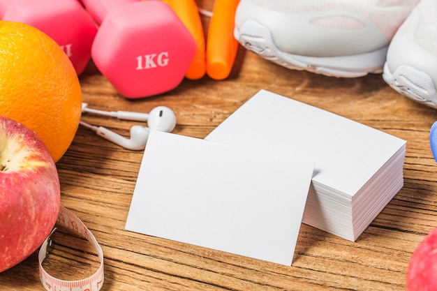 Concepto, botella de agua, mancuernas, zapatos deportivos, smartphone con auriculares y manzanas sobre fondo de madera. Espacio de la copia para el texto. Vista superior