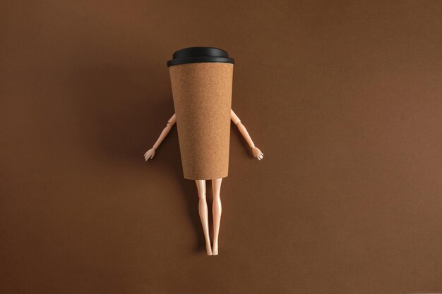 Concepto de café arte minimalista creativo con muñeca y taza de café sobre fondo marrón