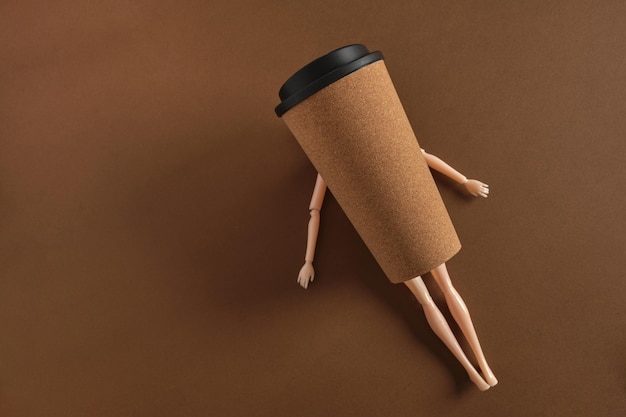 Concepto de café arte minimalista creativo con muñeca y taza de café sobre fondo marrón