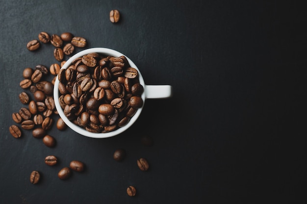 Concepto de café con granos de café en taza sobre la mesa oscura. Vista superior.