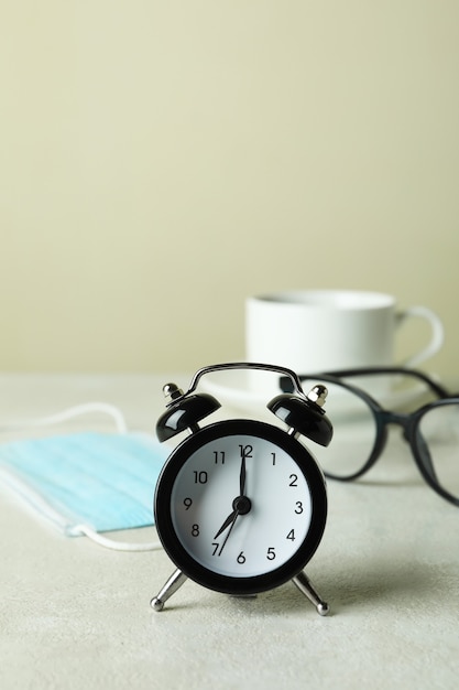 Concepto de café de la mañana con reloj despertador, gafas y máscara