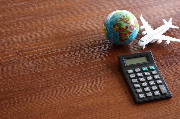 Concepto de cálculo de costos de viaje Avión de juguete globo terráqueo y calculadora en mesa de madera