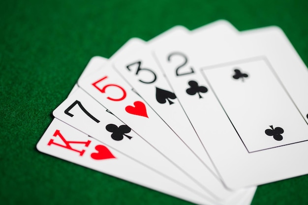 concepto de casino, juegos de azar, juegos de azar, peligro y entretenimiento: mano de póquer de naipes sobre tela verde