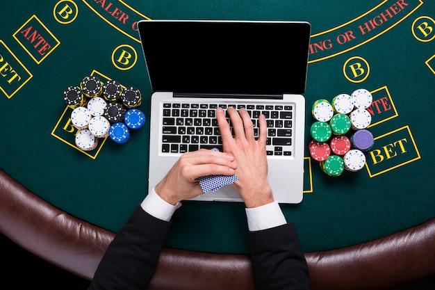 Concepto de casino, juegos de azar en línea, tecnología y personas - cerca del jugador de póquer con naipes